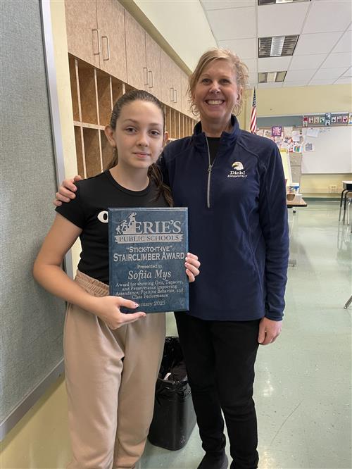 Sophia Mys, Diehl's Stairclimber for the month of January, poses with her plaque and a school staff member.